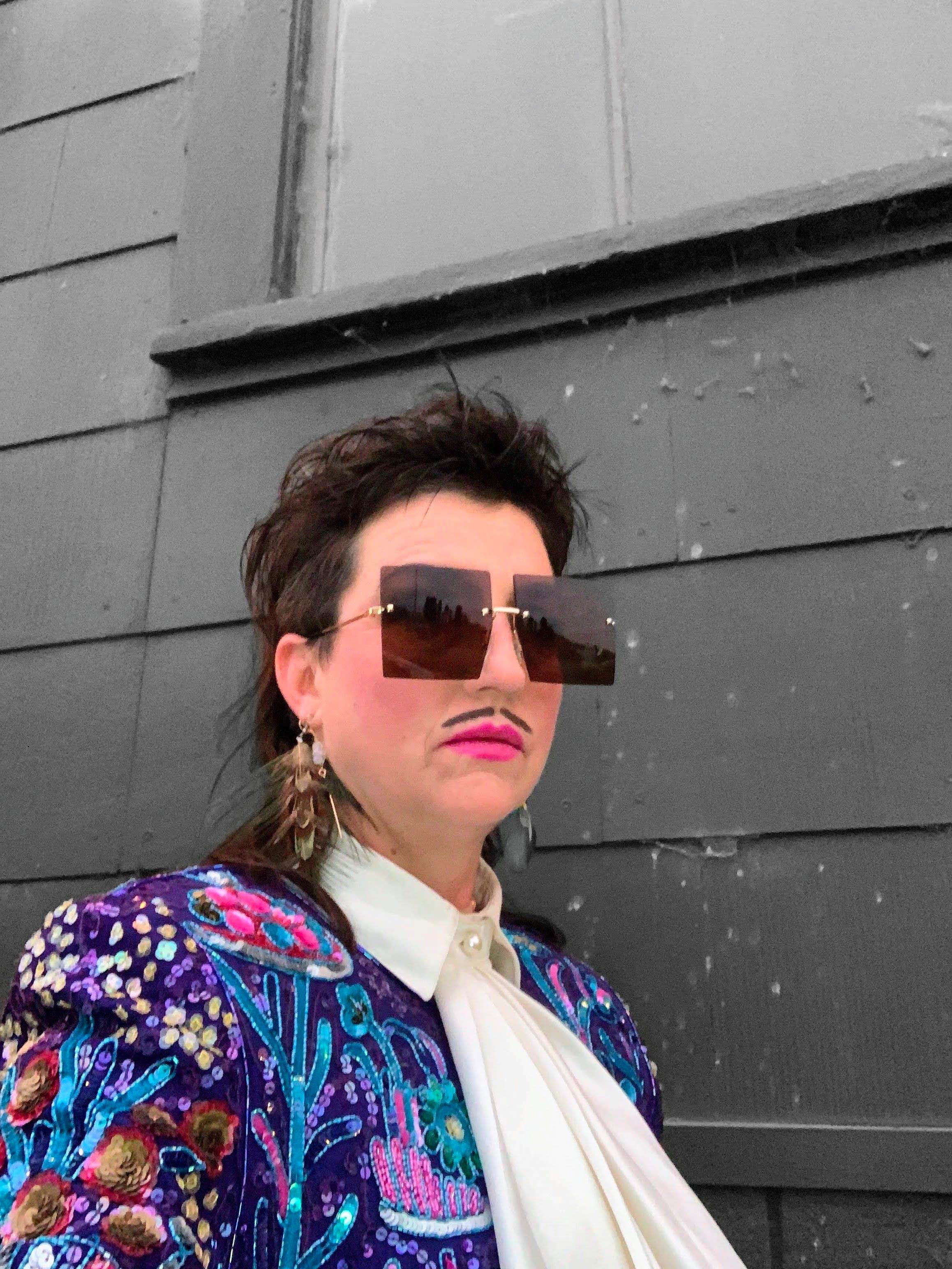a woman wearing a colorful jacket and sunglasses